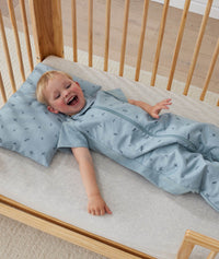 Toddler lying in an ergoPouch Sleep Suit Sack 1.0 TOG Dragonflies, a sleeping bag that converts to a sleeping bag with legs