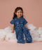 Smiling toddler sitting on a cloud, wearing an ergoPouch Sleep Suit Sack 1.0 TOG Starbeam, a sleeping bag that converts to a sleep suit with legs.