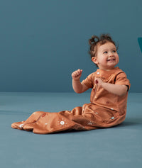 Child sitting in an ergoPouch Sleep Suit Sack 1.0 TOG Sunny, a sleeping bag that converts to a sleeping bag with legs