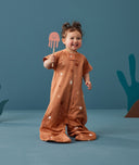 Child standing in an ergoPouch Sleep Suit Sack 1.0 TOG Sunny, a sleeping bag that converts to a sleeping bag with legs