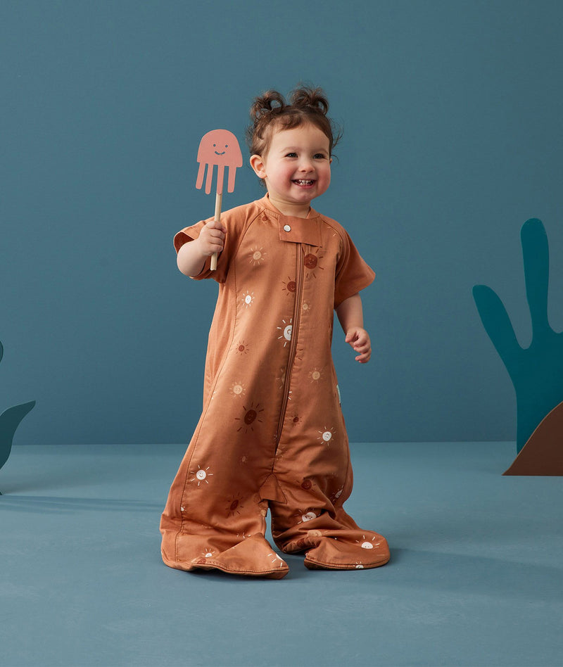 Child standing in an ergoPouch Sleep Suit Sack 1.0 TOG Sunny, a sleeping bag that converts to a sleeping bag with legs