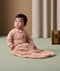 A baby sitting on the floor wearing ergoPouch Sleep Suit Sack with long sleeves and a front zipper. 