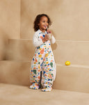 Child standing in an ergoPouch Sleep Suit Sack 2.5 TOG Fruit Salad, a warm sleeping bag that converts to a sleeping bag with legs