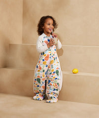 Child standing in an ergoPouch Sleep Suit Sack 3.5 TOG Fruit Salad, a warm sleeping bag that converts to a sleeping bag with legs