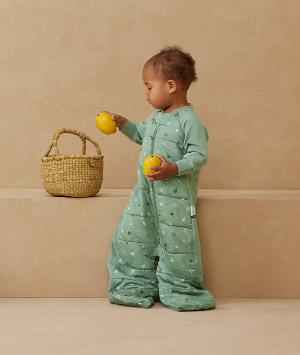 Child standing in an ergoPouch Sleep Suit Sack 3.5 TOG Sweet Orchard, a warm sleeping bag that converts to a sleeping bag with legs