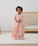 Toddler standing, wearing an ergoPouch Sleep Suit Sack 3.5 TOG Daisies