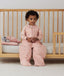 Child sitting in an ergoPouch Sleep Suit Sack 2.5 TOG Daisies, a warm sleeping bag that converts to a sleeping bag with legs