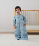 Child standing in an ergoPouch Sleep Suit Sack 2.5 TOG Dragonflies, a warm sleeping bag that converts to a sleeping bag with legs