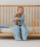 Toddler sitting in crib on a ergoPouch Organic Toddler Pillow And Case Dragonflies, designed to support the correct alignment of the neck during sleep