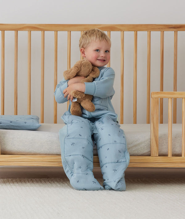 Child sitting in an ergoPouch Sleep Suit Sack 3.5 TOG Dragonflies, a warm sleeping bag that converts to a sleeping bag with legs