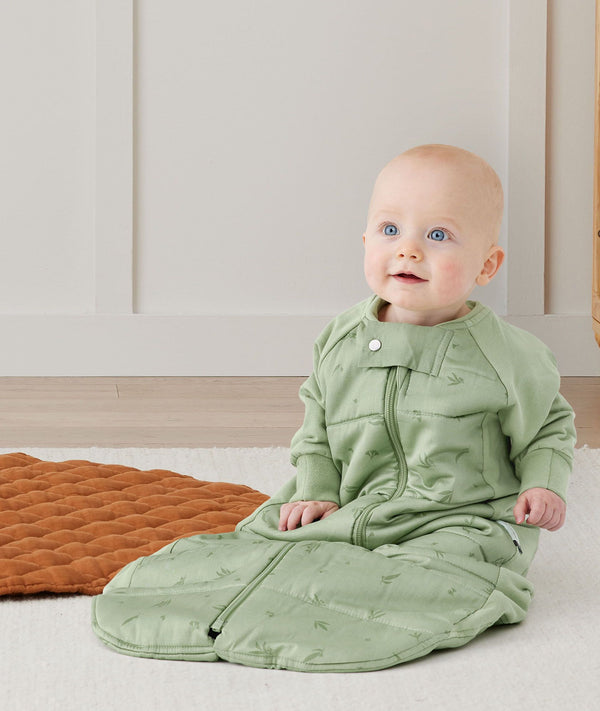 Child sitting in an ergoPouch Sleep Suit Sack 2.5 TOG Willow, a warm sleeping bag that converts to a sleeping bag with legs