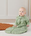 Child sitting in an ergoPouch Sleep Suit Sack 3.5 TOG Willow, a warm sleeping bag that converts to a sleeping bag with legs
