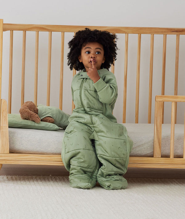 Child sitting in an ergoPouch Sleep Suit Sack 3.5 TOG Willow, a warm sleeping bag that converts to a sleeping bag with legs