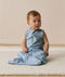 Infant wearing an ergoPouch Sleep Sack 0.2 TOG Dragonflies, sitting on a white mat