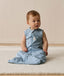 Infant wearing an ergoPouch Sleep Sack 0.2 TOG Dragonflies, sitting on a white mat