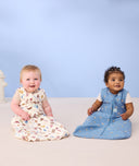 Two infant babies sitting on the floor wearing ergoPouch Sleep Sack 1.0 TOG in Bon Appetit and Petite Pretzel