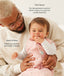 A dad holding a baby wearing a pink, patterned sleep sack over a long-sleeved romper with text highlighting TOG rating feature and wash & wear care.