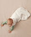 Baby crawling on a plain surface while wearing an oatmeal-colored sleep sack over a green long sleeved romper.