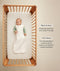 Infant wearing a sleeveless Sleep Sack lying inside a wooden crib with text highlighting wash & wear and TOG rating features.