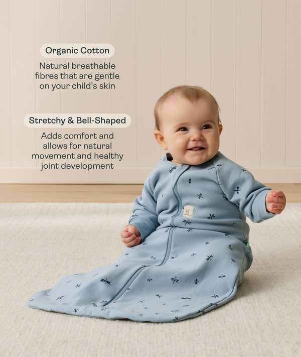 Smiling infant wearing a sleeved Sleep Sack 1.0 TOG Dragonflies with text highlighting organic cotton and stretchy & bell-shaped design.