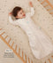 Infant lying in a wooden crib wearing a a long-sleeved Sleep Sack in Oatmeal Marle with text highlighting slim fit design for easy transition from swaddling.