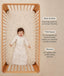Baby lying in a wooden crib wearing a oatmeal-colored long sleeve sleep sack next to product features highlighting Wash & Wear, TOG-Rated, and Sleeved.