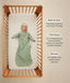 An overhead view of a baby wearing a long-sleeved, sage green leaf-patterned sleep sack lying on their back inside a wooden crib. To the right, text details key features: wash & wear, TOG-rated, and Sleeved.
