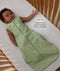 Infant lying in a wooden crib wearing sleeveless Sleep Sack 1.0 TOG Willow with text highlighting slim-fit design for an easy transition from swaddling.