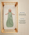 Baby lying on their back inside a wooden crib wearing a green sleeveless Sleep Sack 1.0 TOG with text callouts highlighting wash & wear care and TOG rating features.