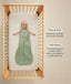 Baby lying on their back inside a wooden crib wearing a green sleeveless Sleep Sack 1.0 TOG with text callouts highlighting wash & wear care and TOG rating features.