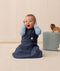 Infant in an ergoPouch Sleep Sack 1.0 TOG Ink sitting on a light wooden floor with a neutral wall background.