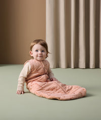 Infant sitting on the floor wearing ergoPouch Sleep Sack 2.5 TOG over a Long Sleeve Romper
