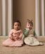 Two babies sitting side by side wearing ergoPouch Sleep Sack 3.5 TOG Sleeved in Elephant Parade and Sleep Sack 2.5 TOG Savannah