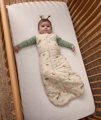 Baby wearing ergoPouch Sleep Sack 2.5 TOG Savannah over a Long Sleeve Romper, lying in a cot