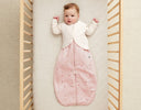 Baby in ergoPouch cocoon swaddle paired with an arm warmer for comfortable sleep.