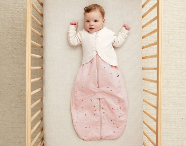 Baby in ergoPouch cocoon swaddle paired with an arm warmer for comfortable sleep.