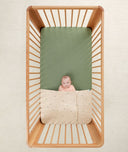 Baby in a crib under an ergoPouch HugMe Blanket in Daisy Sprinkle