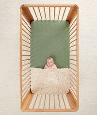 Baby in a crib under an ergoPouch HugMe Blanket in Daisy Sprinkle