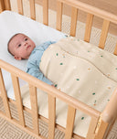 Baby lying arms out under a ergoPouch HugMe Blanket in Daisy Sprinkle