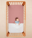 Baby lying in a crib under an ergoPouch HugMe Blanket in Midnight Stripe