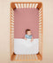 Baby lying in a crib under an ergoPouch HugMe Blanket in Midnight Stripe