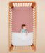 Baby lying in a crib under an ergoPouch HugMe Blanket in Midnight Stripe