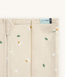 Close-up of a Newborn baby asleep in a bassinet under an ergoPouch HugMe Blanket 0.2 & 1.0 TOG in Daisy Sprinkle displaying the 0.2 TOG side