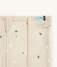Close-up of a Newborn baby asleep in a bassinet under an ergoPouch HugMe Blanket 0.2 & 1.0 TOG in Daisy Sprinkle displaying the 0.2 TOG side