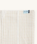 Close-up of a Newborn baby asleep in a bassinet under an ergoPouch HugMe Blanketin Caramel Grid displaying the 0.2 TOG side