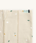 Close-up of a Newborn baby asleep in a bassinet under an ergoPouch HugMe Blanket in Daisy Sprinkle displaying the 1.0 TOG side