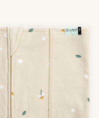 Close-up of a Newborn baby asleep in a bassinet under an ergoPouch HugMe Blanket in Daisy Sprinkle displaying the 1.0 TOG side