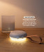 A portable White Noise Machine with a strap sitting on a wooden surface, casting a soft, warm LED light. Text overlay reads 