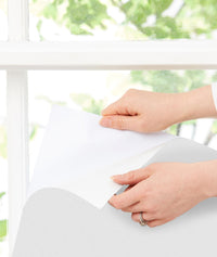 Close up of ergoPouch Window Blockout White being peeled and stuck to the window