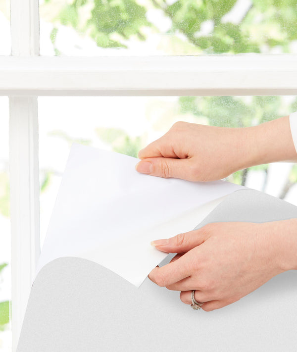 Close up of ergoPouch Window Blockout White being peeled and stuck to the window